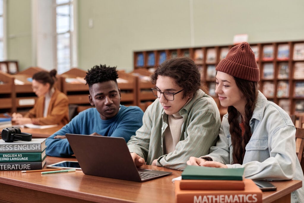 Three Young People Using Laptop in Library